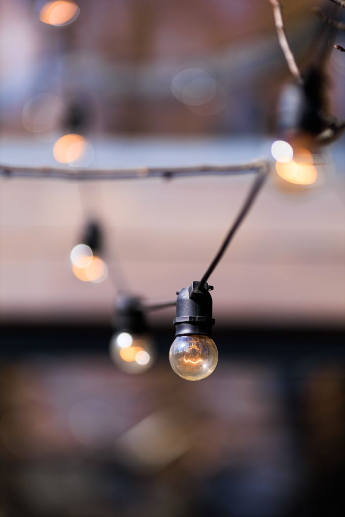 Artistic close-up of outdoor string lights glowing softly at twilight.