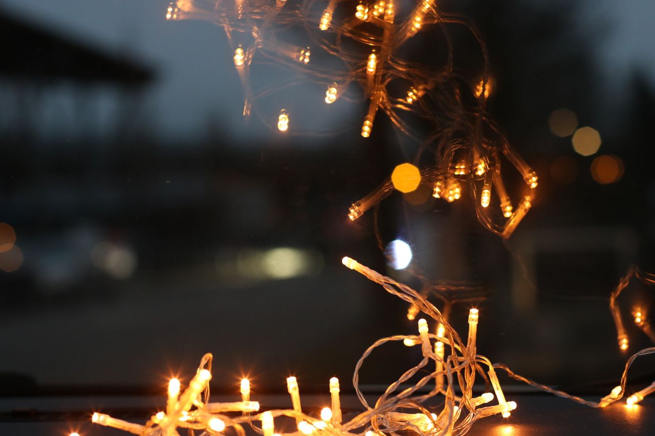A close-up of warm string lights creating a festive reflection in a dark setting.